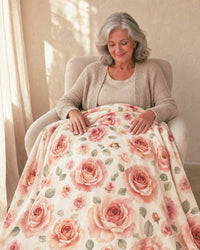 A woman sitting in an armchair with the blanket spread across her lap, her hands resting on the rose print