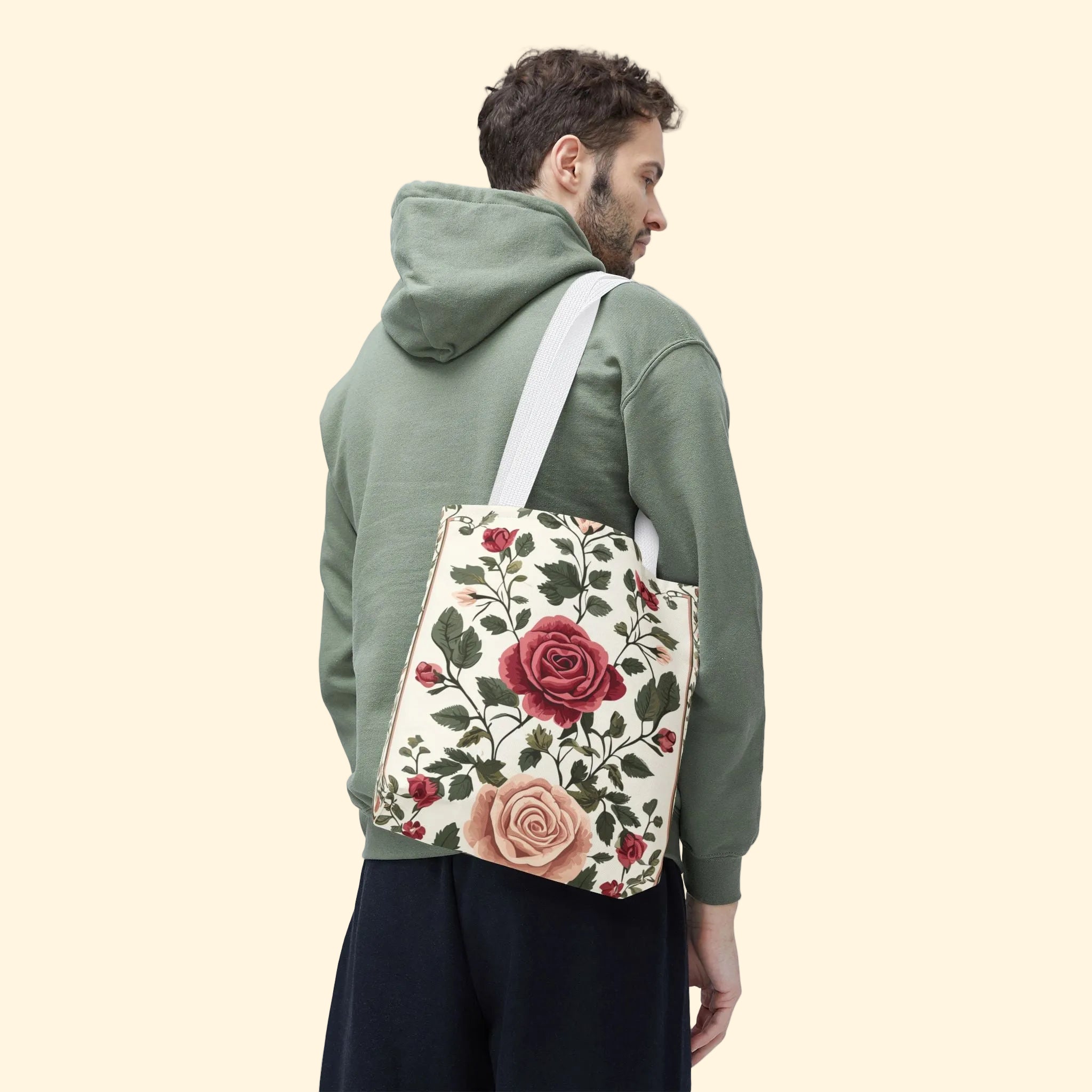 Man wearing a green hoodie with a floral tote bag on a white background