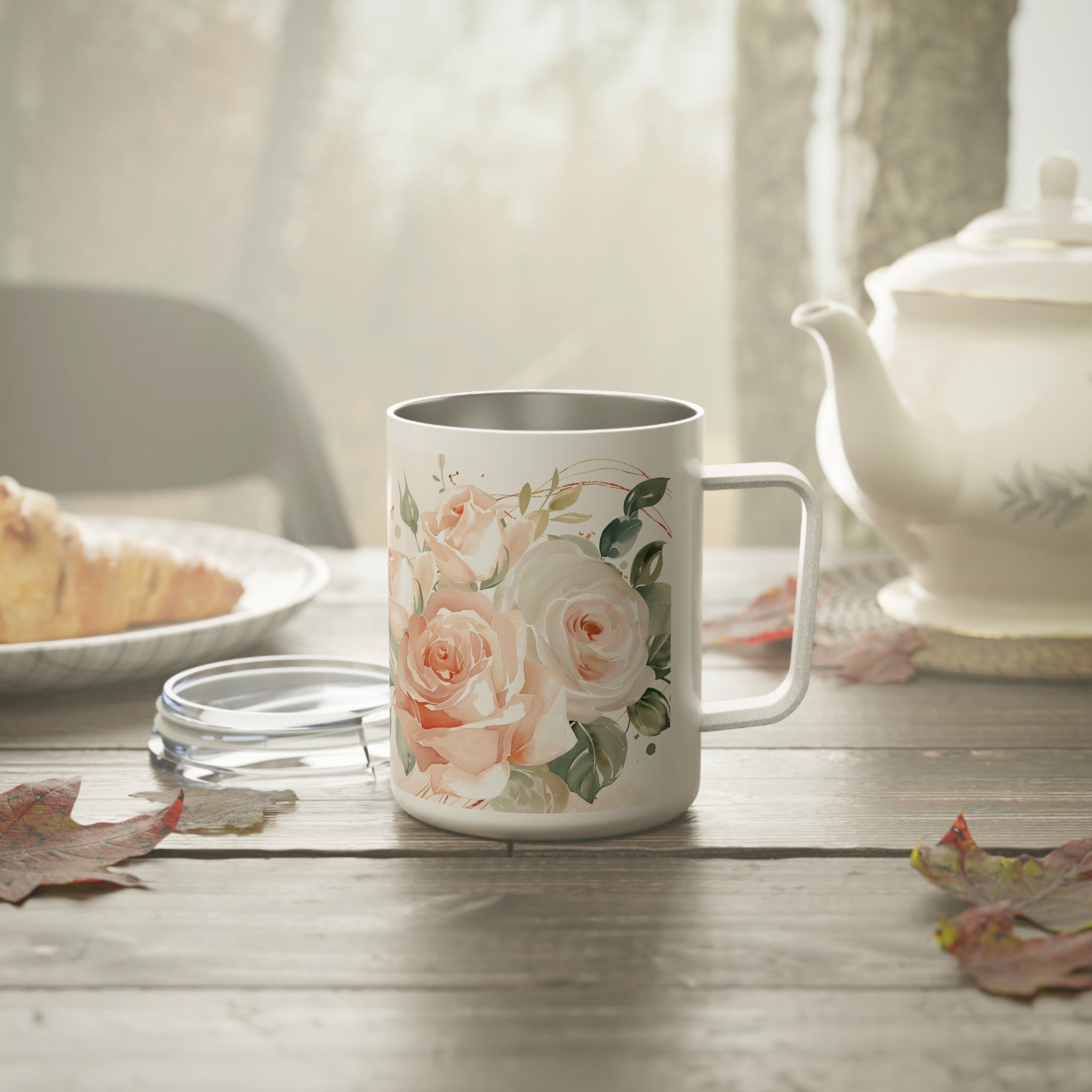 Floral mug on a table with a teapot and croissant in the background